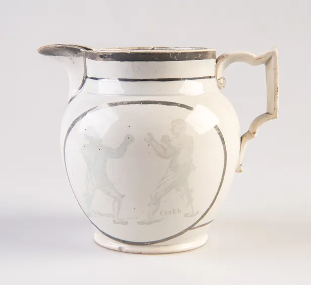 [Pearlware jug decorated with transfer image of Tom Molineux and Tom Cribb facing each other in a boxing match, a verse to the other side.]